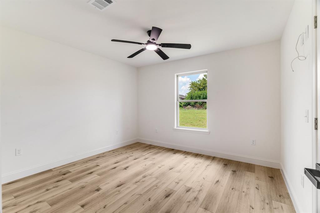 306 Sunset Street Roxton, TX 75477 - Photo 21 of 26 an empty room with wooden floor ceiling fan and window