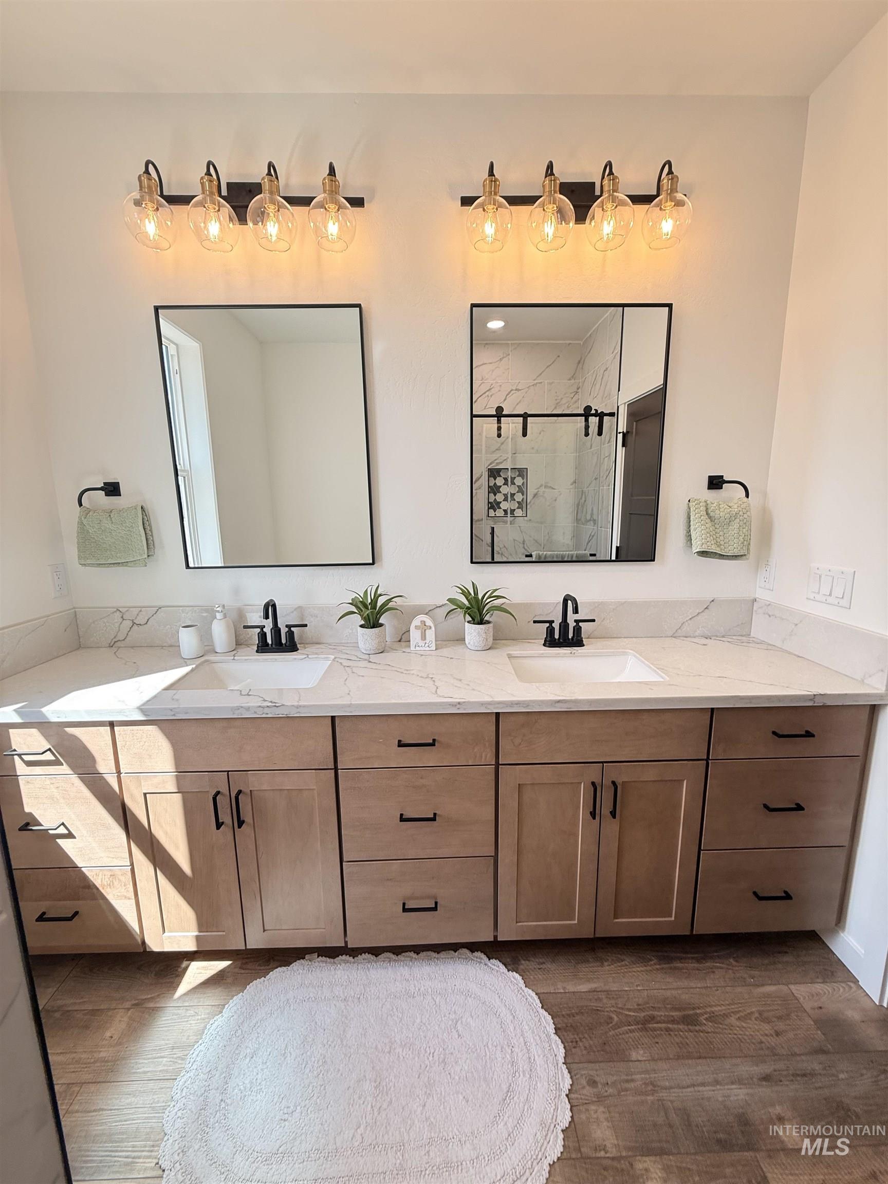 1220 Bronze Rupert, ID 83350 - Photo 20 of 30 Dual vanity featuring light wood-finish cabinetry, white countertops, undermount sinks, and matte black fixtures