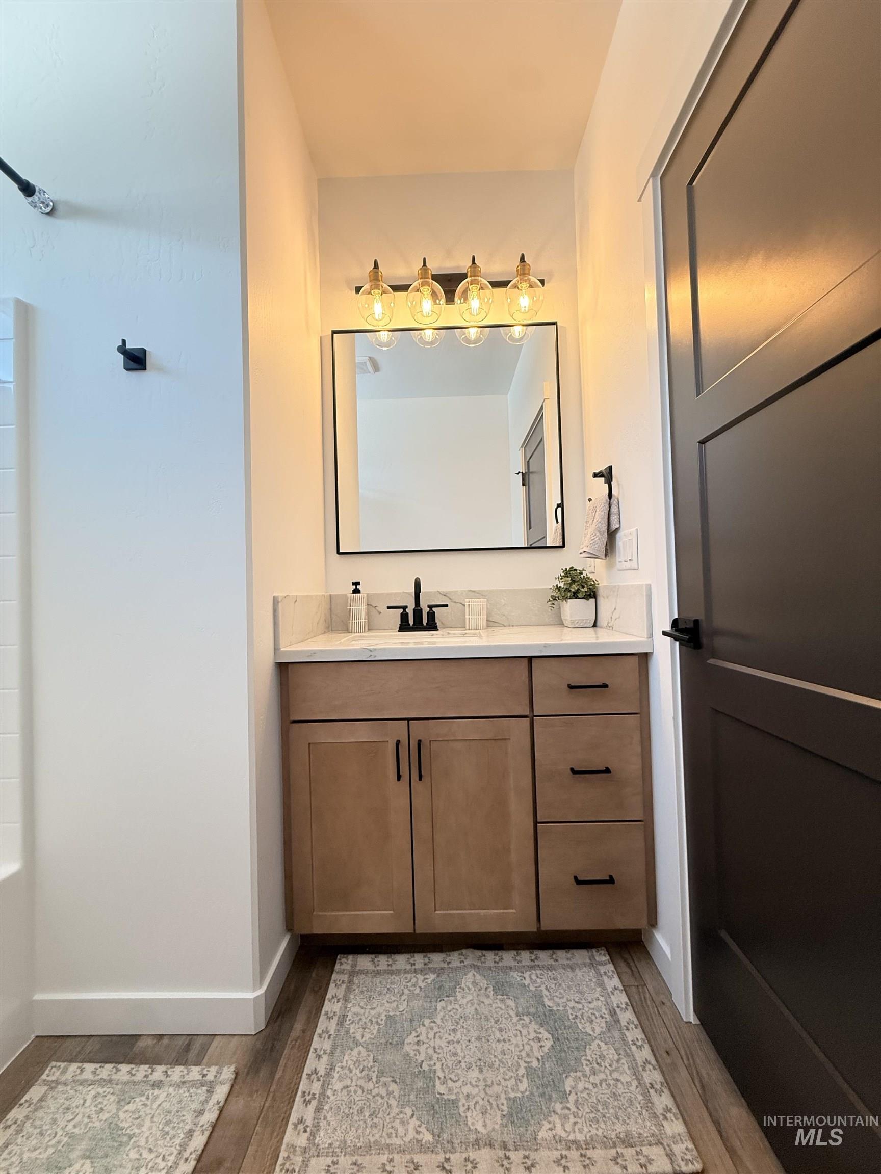1220 Bronze Rupert, ID 83350 - Photo 22 of 30 Bathroom vanity featuring wood-finish cabinetry, a stone countertop, and a rectangular mirror