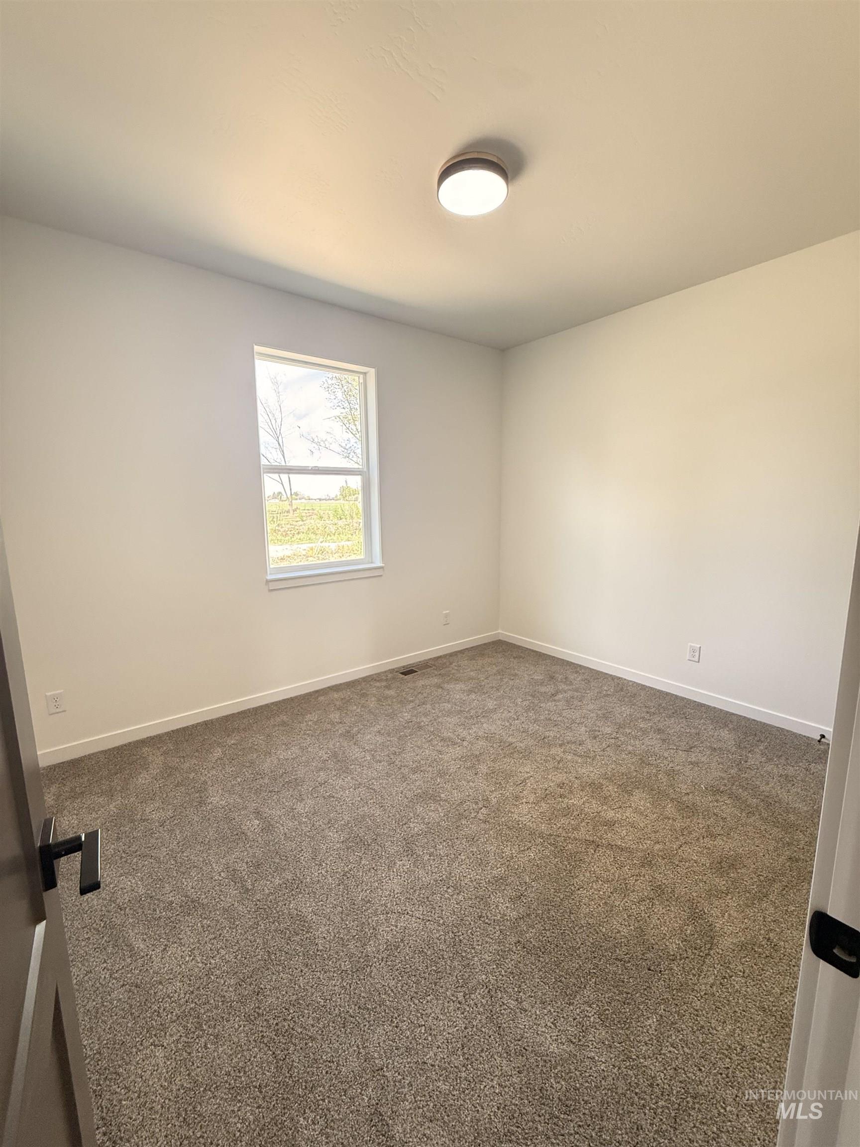 1220 Bronze Rupert, ID 83350 - Photo 24 of 30 Room featuring neutral-toned carpet, white walls, and a single window with a framed exterior landscape