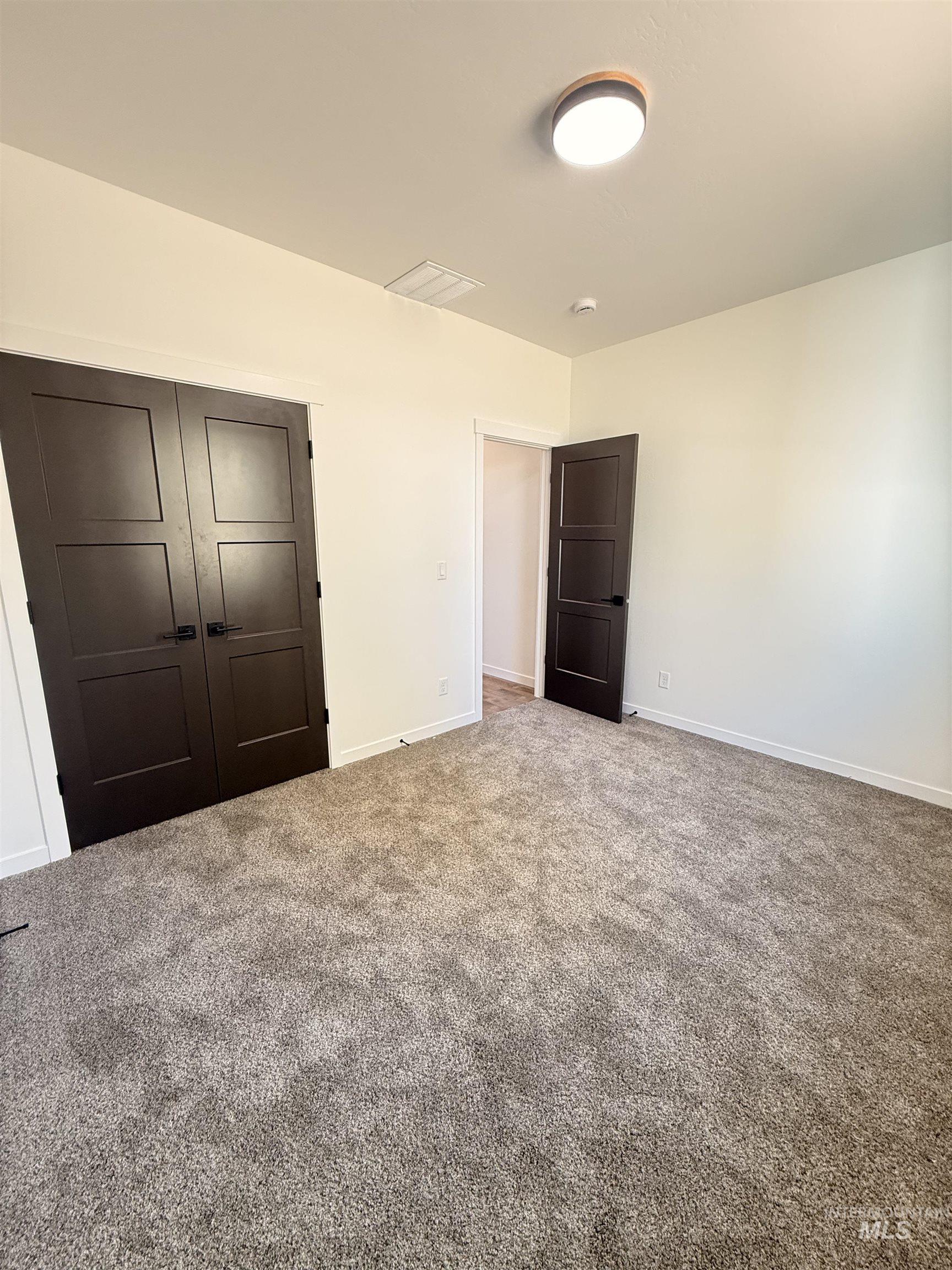 1220 Bronze Rupert, ID 83350 - Photo 25 of 30 Spacious room featuring neutral carpeting, light-toned walls, and dark paneled doors with black hardware