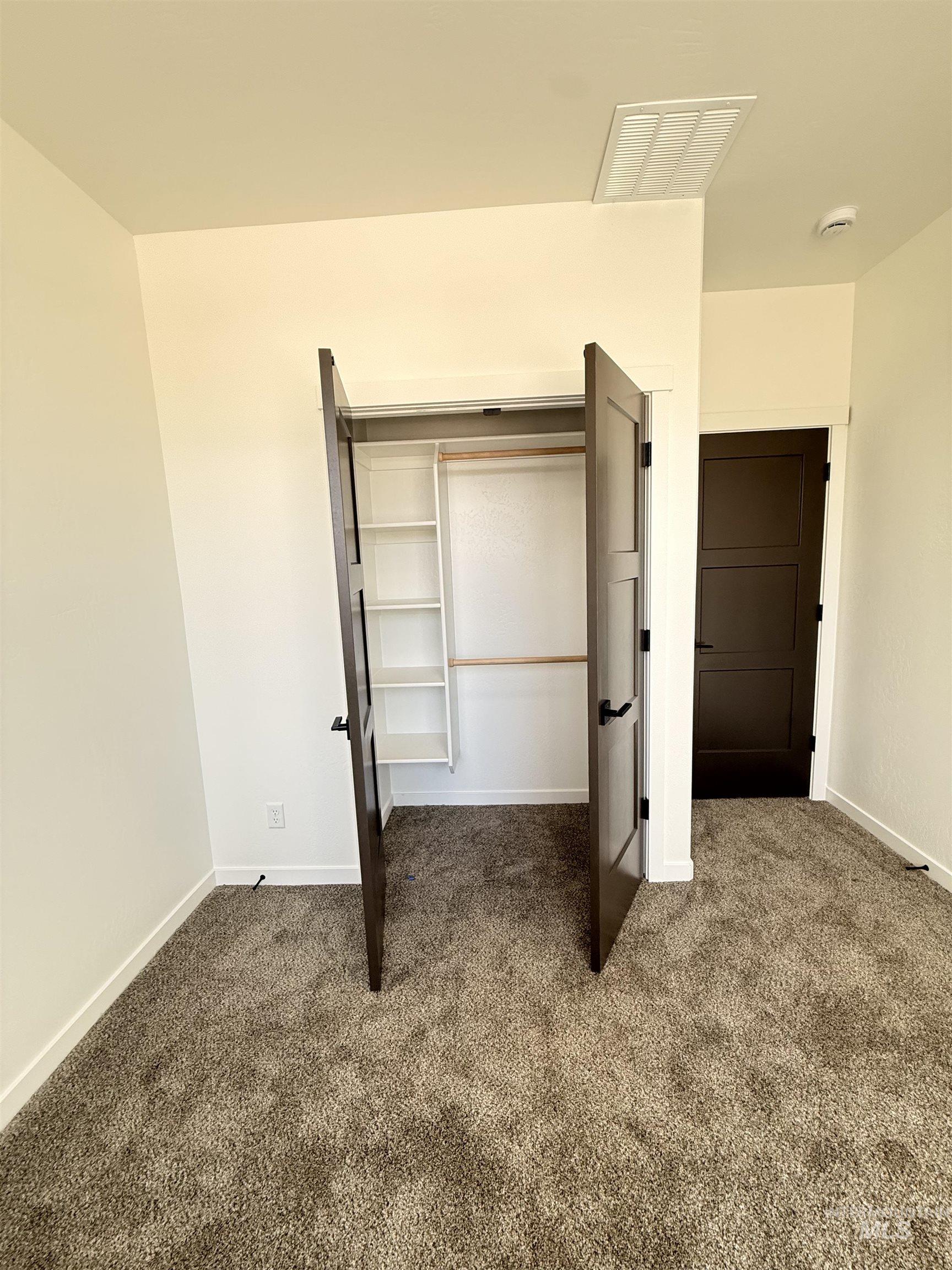 1220 Bronze Rupert, ID 83350 - Photo 26 of 30 Built-in closet with double doors and shelving, textured carpet flooring, white baseboards, and a dark interior door