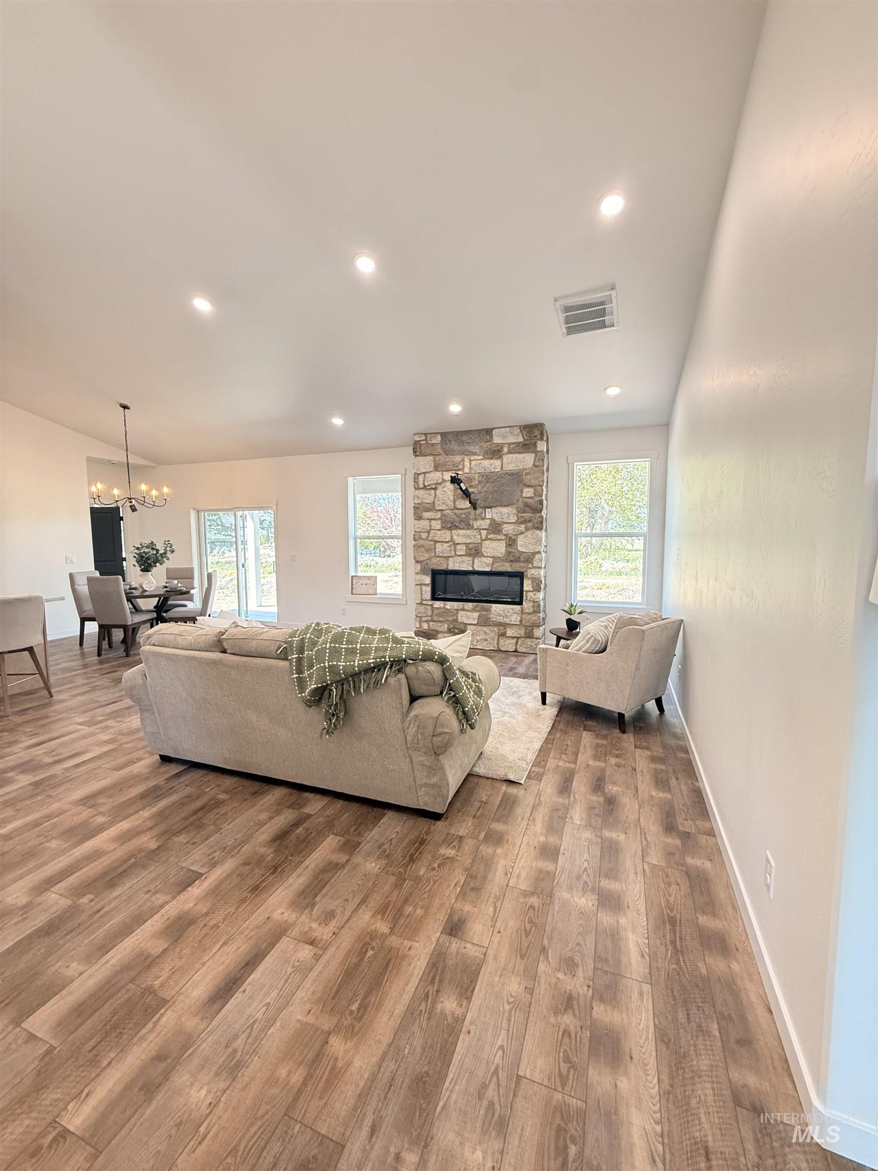 1220 Bronze Rupert, ID 83350 - Photo 7 of 30 Spacious living area featuring wood-finish flooring, a stone-clad fireplace, recessed lighting, and ample natural light from multiple windows