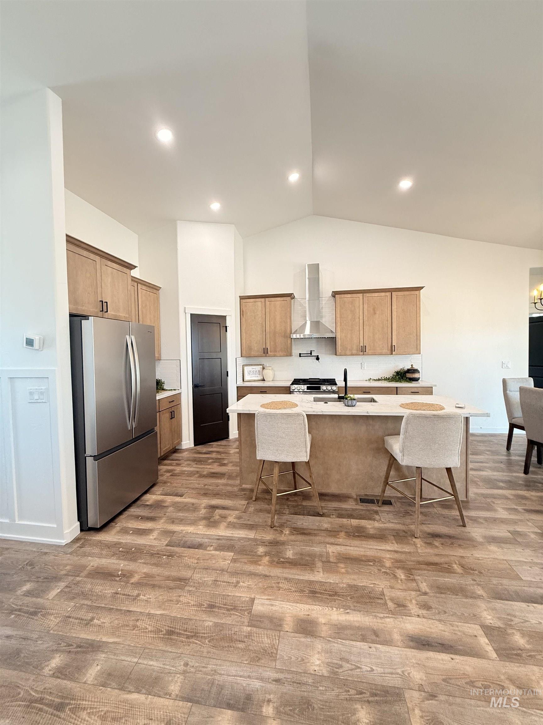 1220 Bronze Rupert, ID 83350 - Photo 10 of 30 Kitchen featuring stainless steel appliances, wood-finish flooring, a large island with countertop seating, recessed lighting, and vaulted ceilings