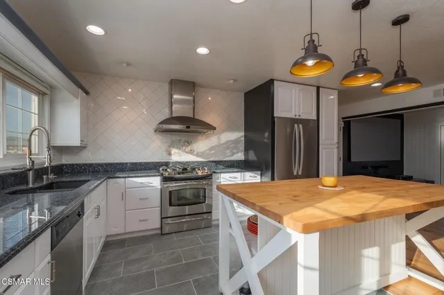 a kitchen with stainless steel appliances granite countertop a sink a stove and a refrigerator