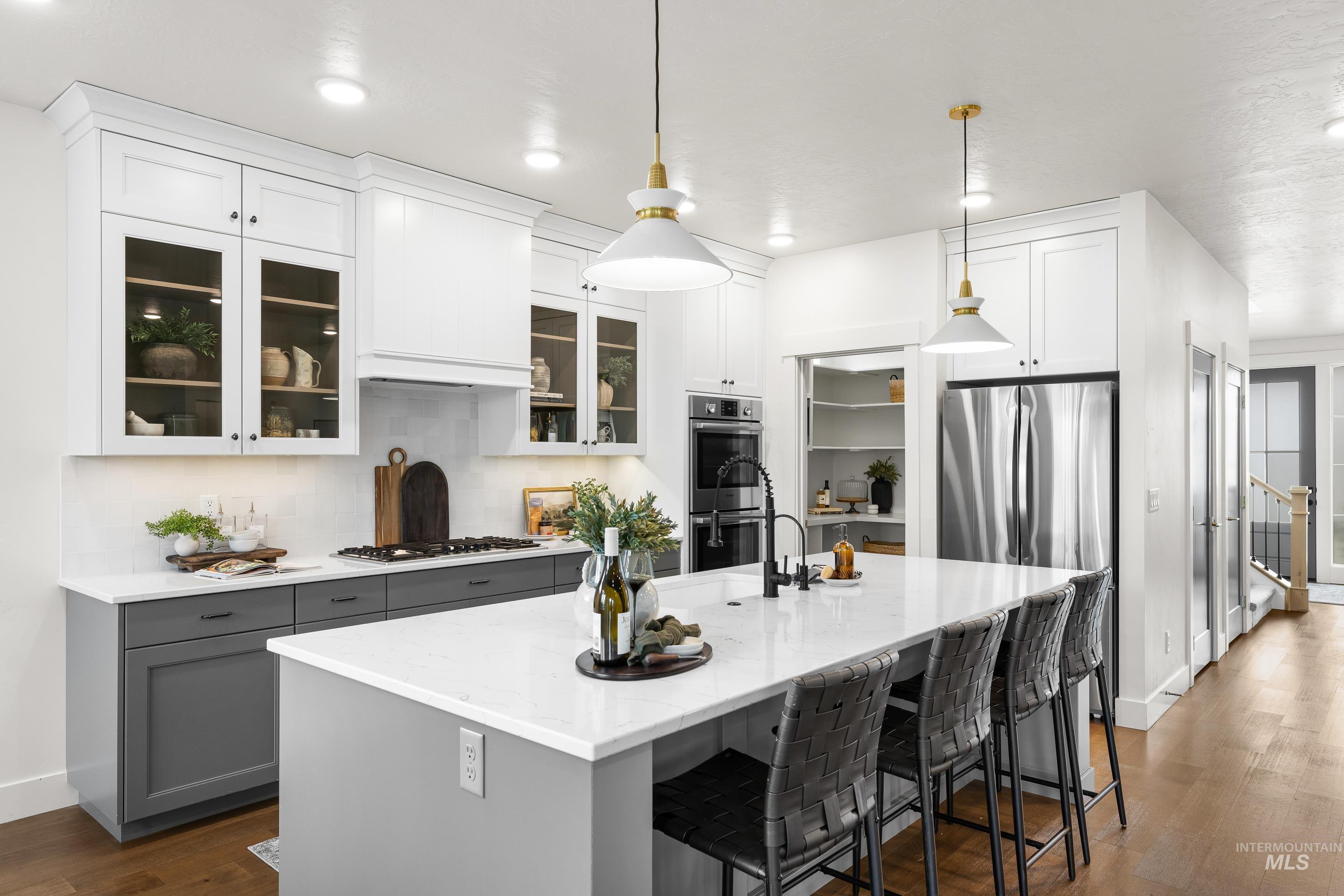 747 South Short Road Eagle, ID 83616 - Photo 11 of 48 Dual tone kitchen featuring dark wood-style flooring, a kitchen breakfast bar, light stone countertops, backsplash, and an island with sink