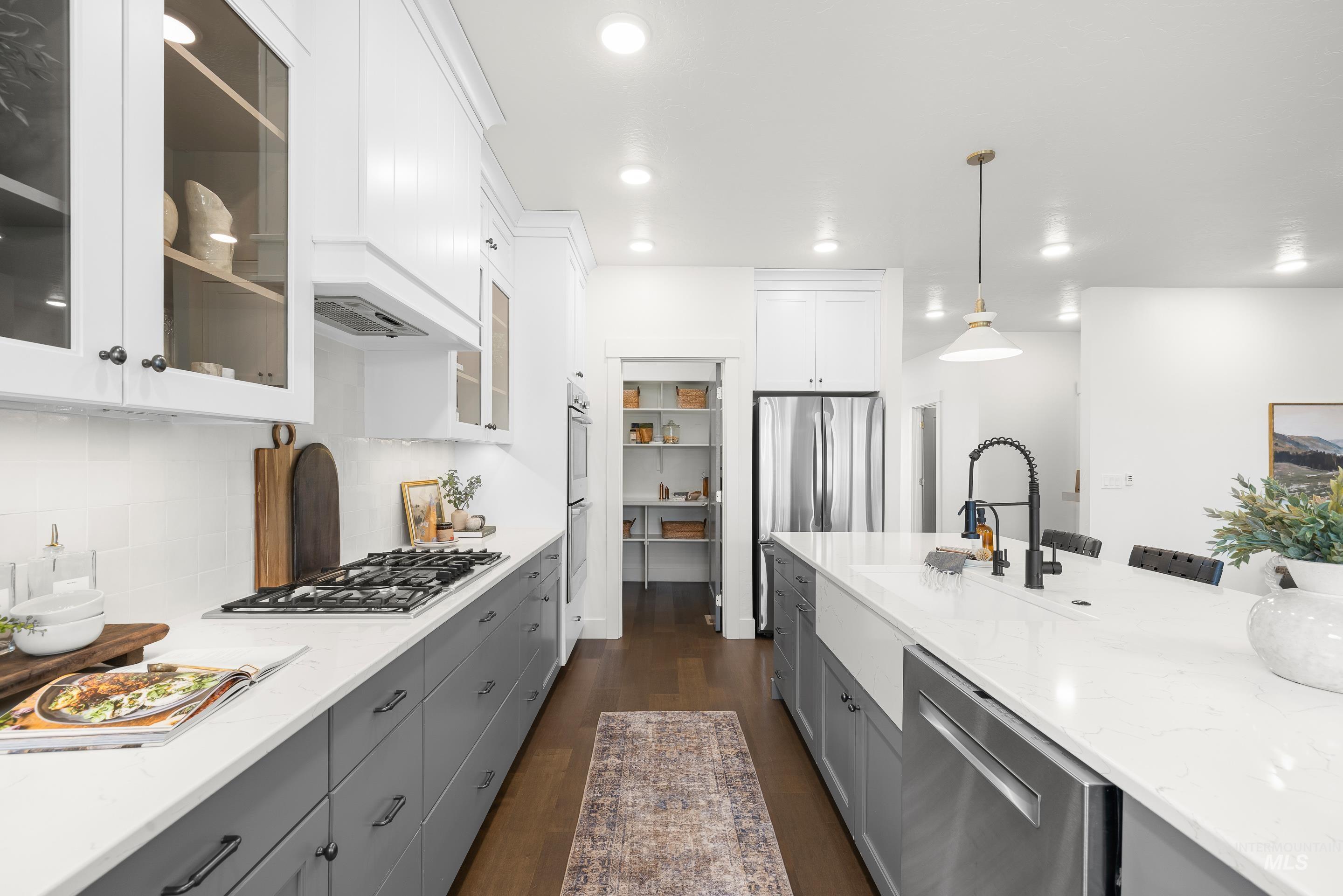 747 South Short Road Eagle, ID 83616 - Photo 12 of 48 Kitchen with pendant lighting, stainless steel appliances, dark wood-style flooring, light stone countertops, and glass insert cabinets