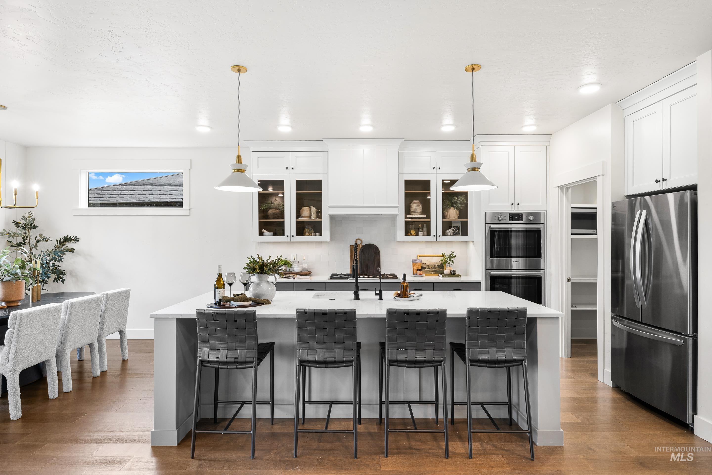 747 South Short Road Eagle, ID 83616 - Photo 13 of 48 Kitchen with pendant lighting, a kitchen bar, stainless steel appliances, light wood-style floors, and glass fronted cabinets