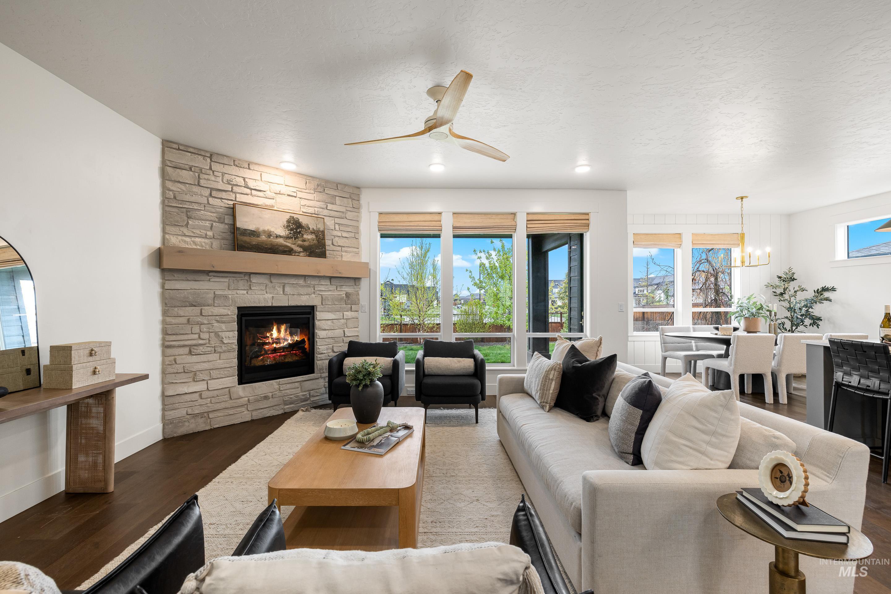 747 South Short Road Eagle, ID 83616 - Photo 6 of 48 Living area with ceiling fan, wood finished floors, a stone fireplace, a textured ceiling, and suspended lighting