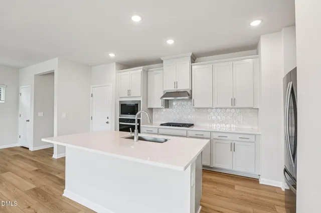 a kitchen with a sink a stove a refrigerator and white cabinets
