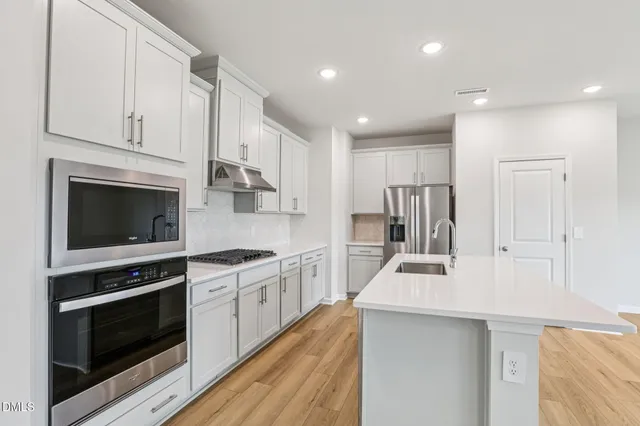 a view of kitchen with kitchen island stainless steel appliances wooden floor and window
