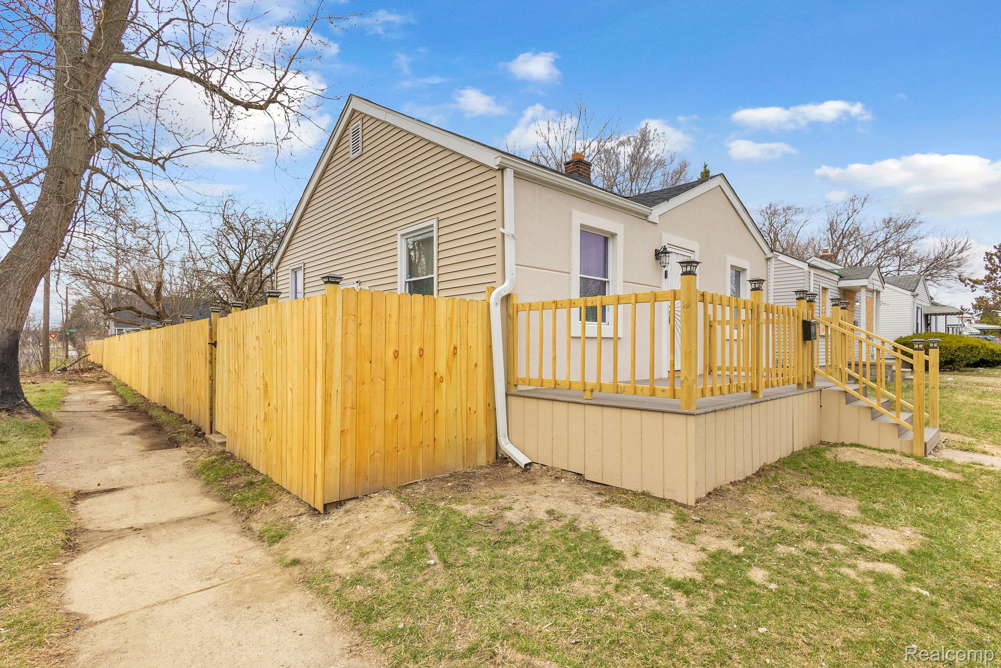 8401 Fielding Street Detroit, MI 48228 - Photo 32 of 34 View of home's exterior featuring a chimney, stucco siding, and a wooden deck