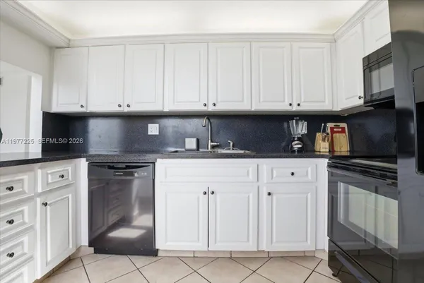 a kitchen with white cabinets and black appliances