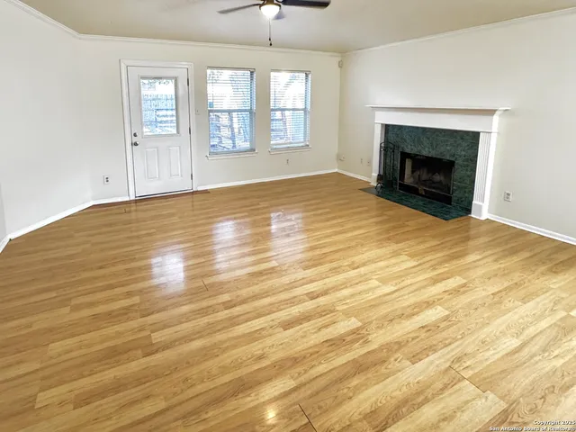 an empty room with wooden floor fireplace and windows