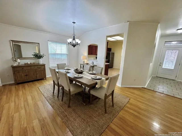a dining room with wooden floor a chandelier a wooden table and chairs