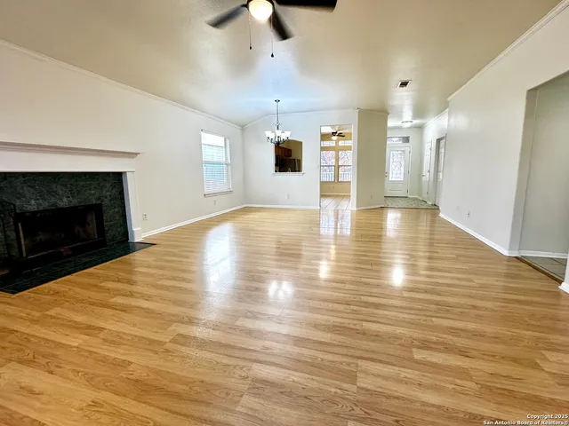 a view of an empty room with wooden floor and a fireplace