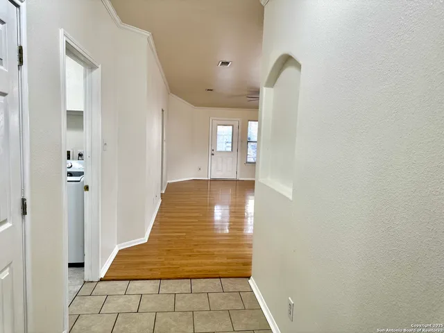 a view of a hallway with wooden floor and a bathroom