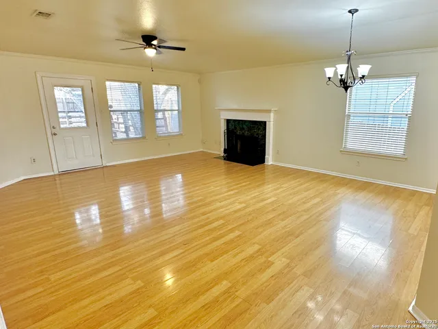 a view of an empty room with chandelier and wooden floor