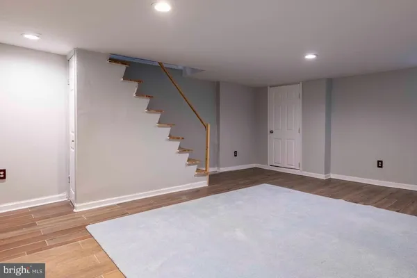 a view of an empty room with wooden floor and stairs