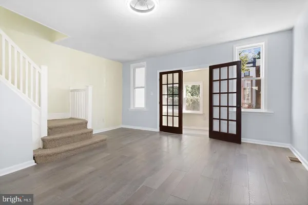 an empty room with wooden floor and windows