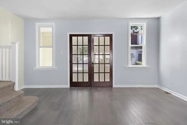 an empty room with wooden floor and windows
