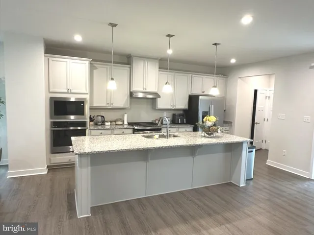 a large kitchen with stainless steel appliances a large counter top a stove a refrigerator and cabinets