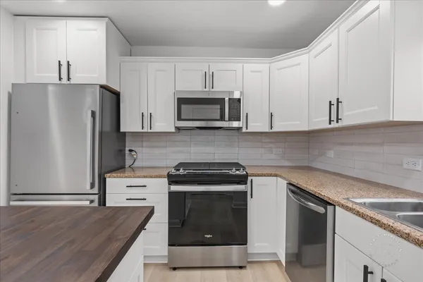 a kitchen with granite countertop a stove a refrigerator and a sink