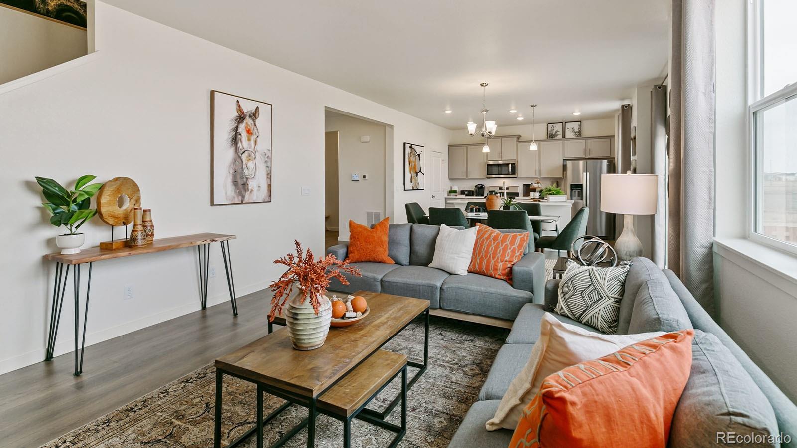 801 South Apex Avenue Fort Lupton, CO 80621 - Photo 13 of 26 a living room with furniture and a dining table with wooden floor