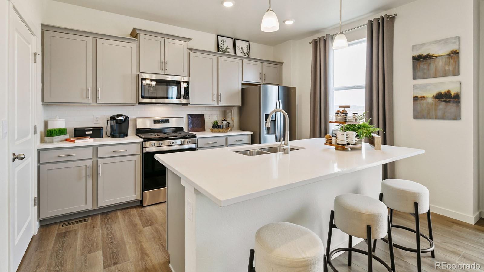 801 South Apex Avenue Fort Lupton, CO 80621 - Photo 6 of 26 a kitchen with white cabinets and stainless steel appliances