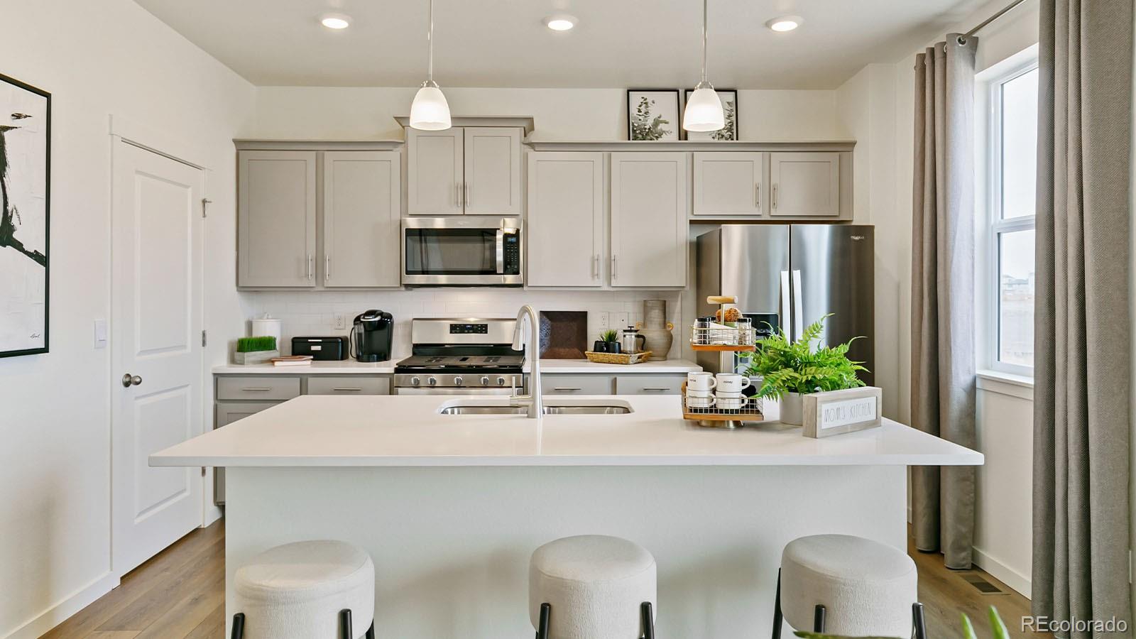 801 South Apex Avenue Fort Lupton, CO 80621 - Photo 7 of 26 a kitchen with stainless steel appliances a white refrigerator a stove a microwave and cabinets