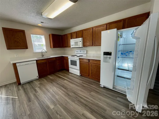 a kitchen with stainless steel appliances granite countertop a refrigerator a stove top oven a sink and dishwasher