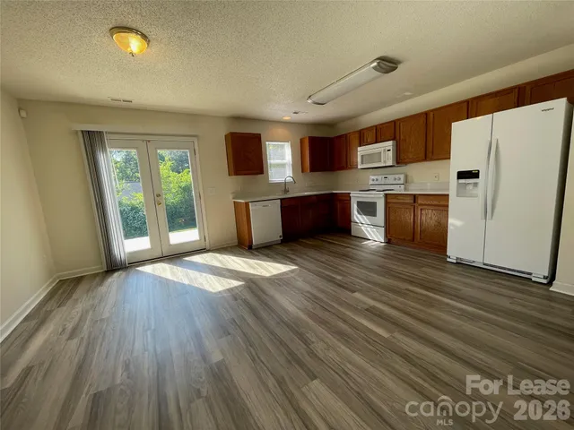 a large kitchen with stainless steel appliances wooden floors and large window