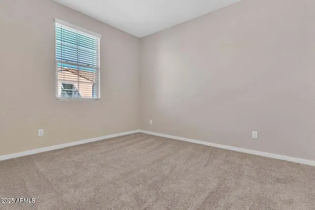 an empty room with chandelier fan and windows
