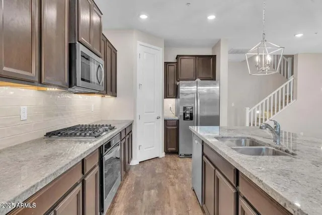 a large kitchen with granite countertop a sink a counter top space stainless steel appliances and cabinets