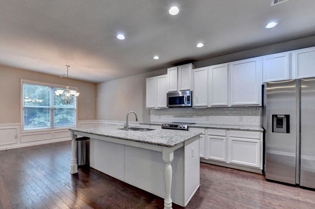 5166 Apple Grove Road Northeast Buford, GA 30519 - Photo 12 of 29 a kitchen with stainless steel appliances granite countertop a stove a sink a refrigerator and white cabinets with wooden floor