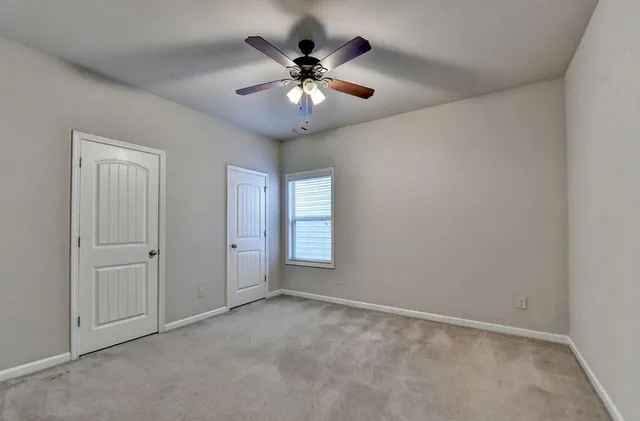 an empty room with ceiling fan and window