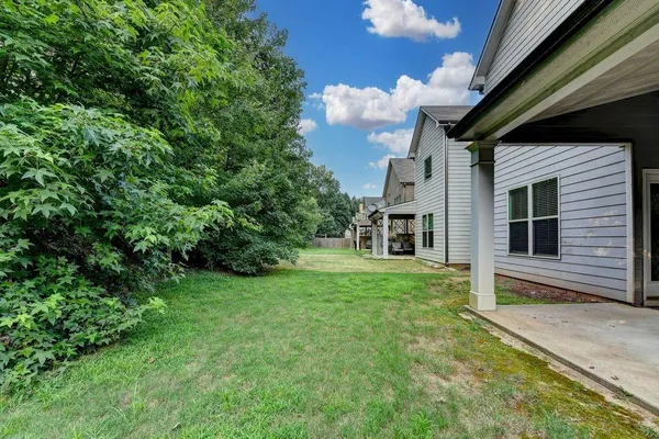a view of house in front of a big yard with large trees