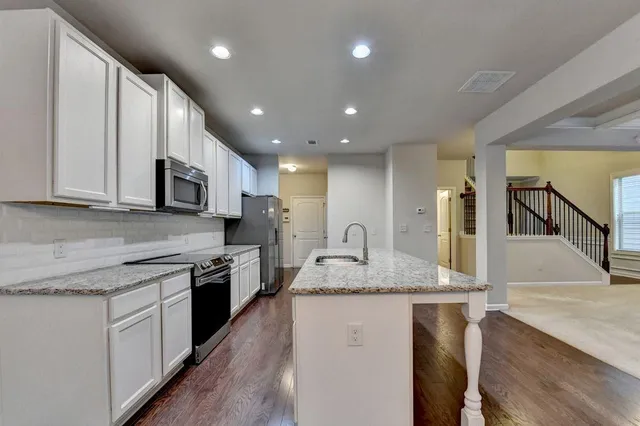 a kitchen with stainless steel appliances granite countertop a sink a stove top oven a counter space and cabinets