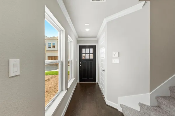 a view of a hallway with wooden floor and a bathroom