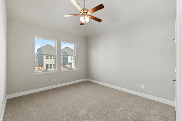 an empty room with chandelier fan and windows