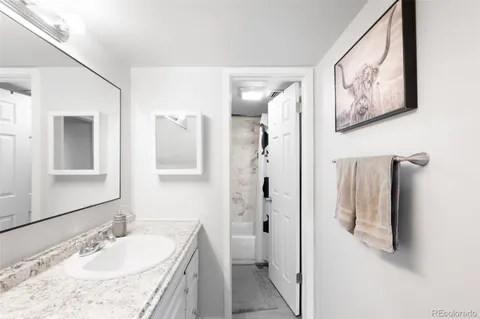 a bathroom with a granite countertop tub sink and mirror