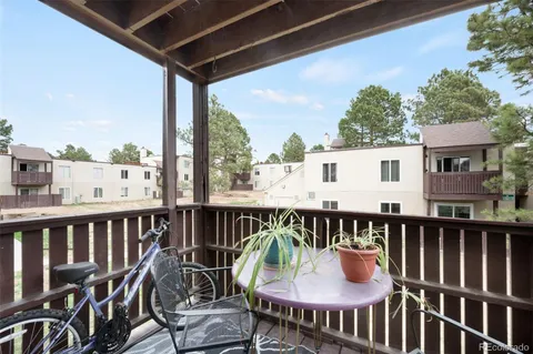 a balcony with wooden floor outdoor seating and yard in the back