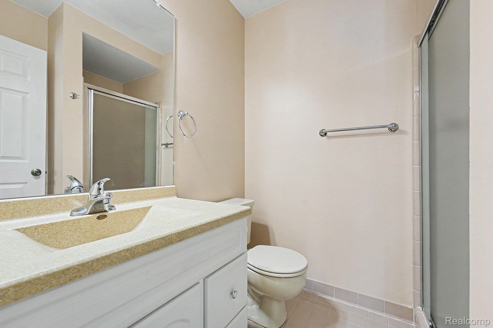 42619 Cedar Ridge Drive Clinton Township, MI 48038 - Photo 12 of 18 Bathroom featuring a vanity with integrated sink, shower stall with sliding glass door, white two-panel door, and tiled flooring