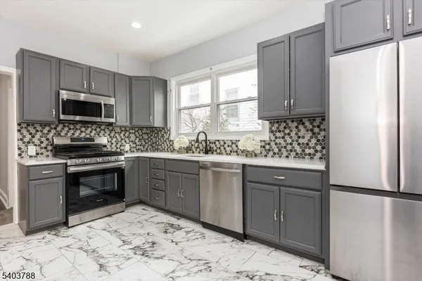 a kitchen with stainless steel appliances granite countertop a refrigerator sink stove microwave and cabinets