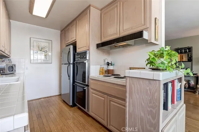 a kitchen with stainless steel appliances granite countertop a refrigerator a stove and a wooden floors