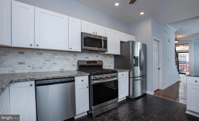 a kitchen with stainless steel appliances granite countertop a refrigerator stove and microwave