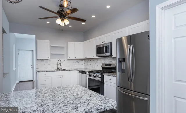 a kitchen with stainless steel appliances granite countertop a refrigerator sink and stove