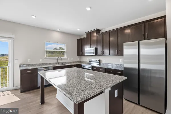 a kitchen with stainless steel appliances granite countertop a kitchen island a cabinets a refrigerator and a sink