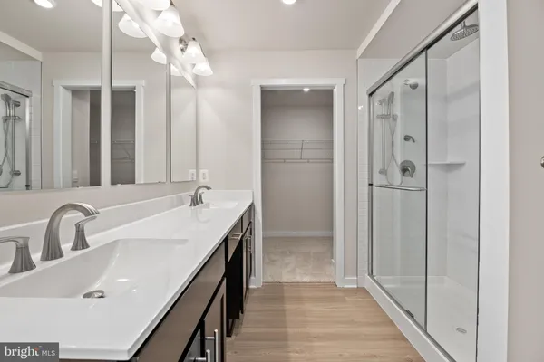a bathroom with a double vanity sink a large mirror and shower