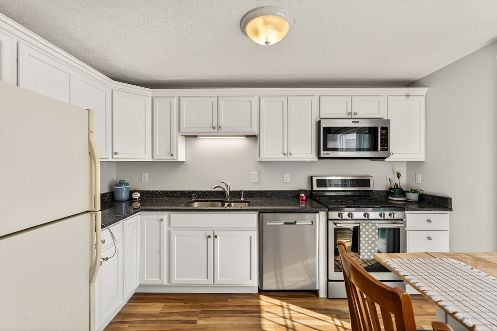 61 Fox Meadow Road, Unit A Leominster, MA 01453 - Photo 8 of 38 a kitchen with granite countertop a stove top oven a sink a counter space and cabinets
